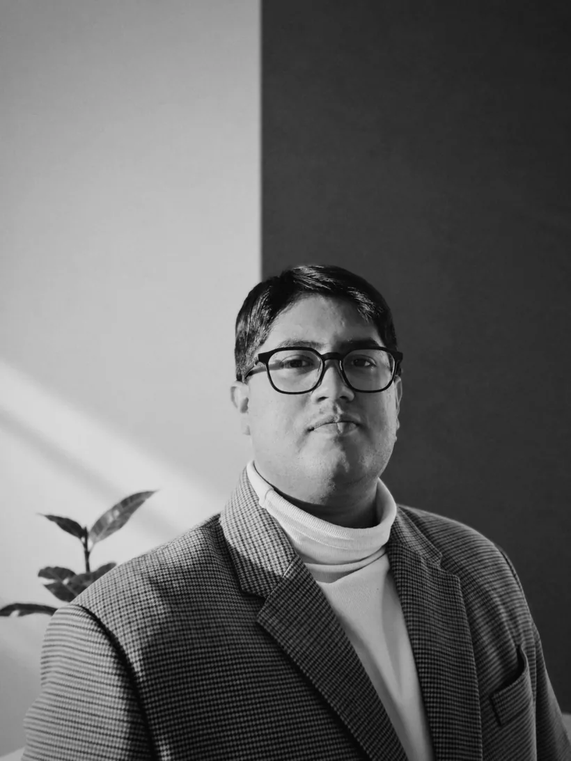 Anindya Mishra, photographed against a wall divided by a hard diagonal of daylight